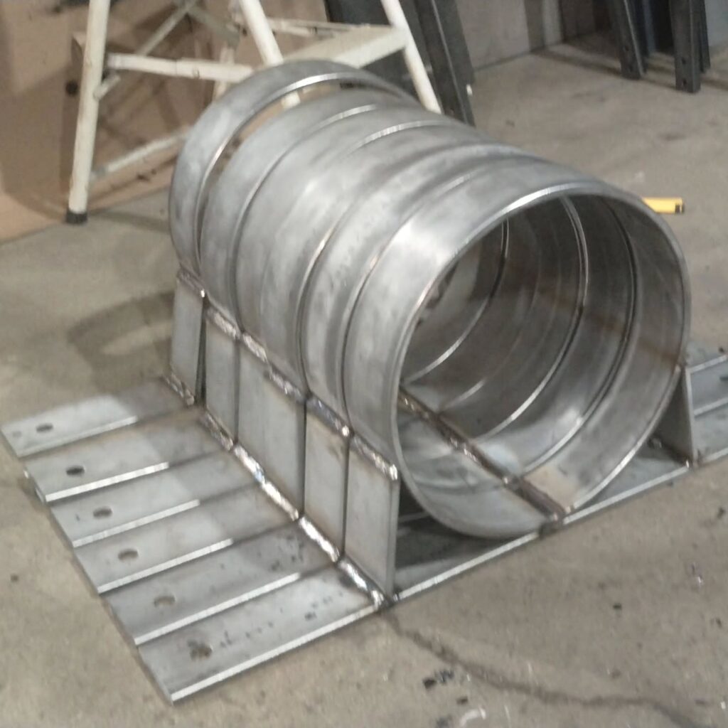 Metal fabrication display featuring a cylindrical structure made of welded steel rings mounted on a flat base, showcasing industrial design and craftsmanship.