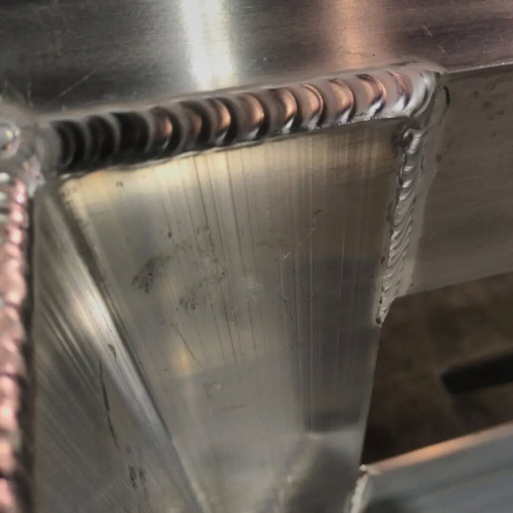 Close-up of a welded aluminum joint, highlighting clean bead patterns and smooth finish. This image illustrates quality welding techniques.